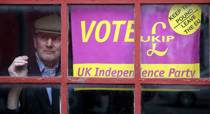 A man looks out of a window next to a political poster in London, May 6, 2015. Source: Reuters