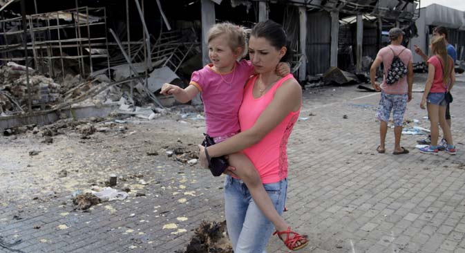 A woman with a child walks past stalls, which were damaged by shelling, at a local market in Donetsk, June 4, 2015. Source: Reuters