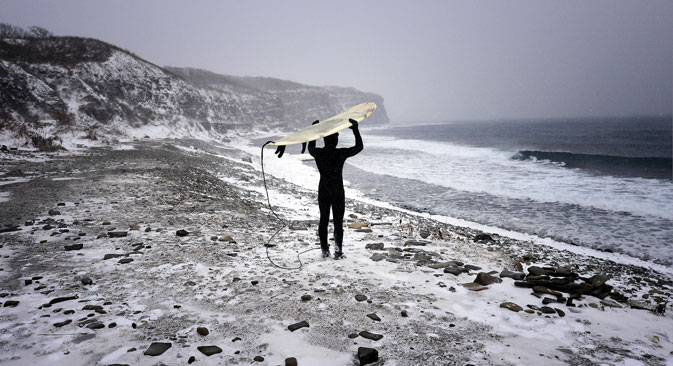 A man with his surfboard walking along the Ussuri Bay coast on Russky Island, Dec. 21, 2014. Source: Yuri Smityuk/TASS