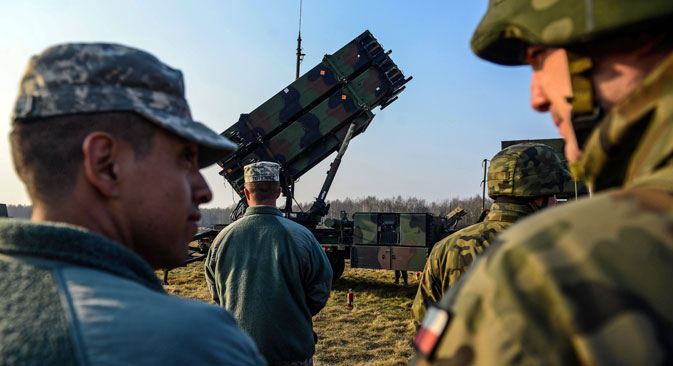 The U.S. (left) and Polish soldiers stand next to a launcher vehicle of a US 'Patriot' air defence guided missile system battery positioned on a military training ground near Sochaczew, Poland, 21 March 2015. Source: EPA / Vostock-photo