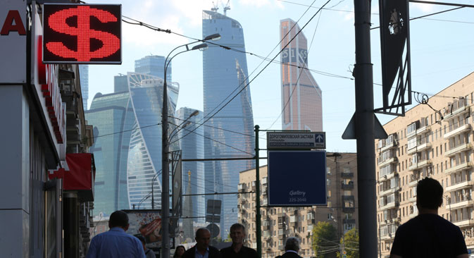 Skyscrapers of the Moscow City business district stand beyond a foreign currency exchange bureau displaying a U.S. dollar sign in Moscow. Source: Getty Images