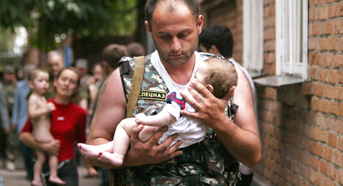A Russian police officer carries a released baby from a school seized by heavily armed masked men and women in the town of Beslan, 2004. Source: Reuters