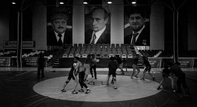 Entraînement de lutte dans un gymnase. Les portraits en arrière-plan de gauche à droite représentent : Akhmad Kadyrov, Vladimir Poutine et Ramzan Kadyrov. Crédit photo : Davide Monteleone