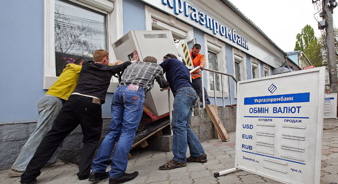 Les ouvriers sortent le distributeur de billets de la banque Ukrgazprombank. Crédit : Taras Litvinenko/RIA Novosti