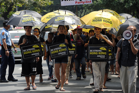Para aktivis Filipina membawa payung yang bertuliskan slogan-slogan dan berbaris menuju kantor konsulat Tiongkok untuk menunjukkan dukungan mereka pada demonstran pro-demokrasi Hong Kong selama unjuk rasa di Manila, 2 Oktober 2014. Foto: AFP/EastNews
