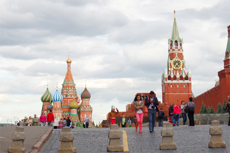 Dua orang turis berjalan dari arah Katederal St. Basil (kiri) dan Menara Spasskaya di Lapangan Merah menuju Lapangan Revolusi di Moskow, Rusia.
