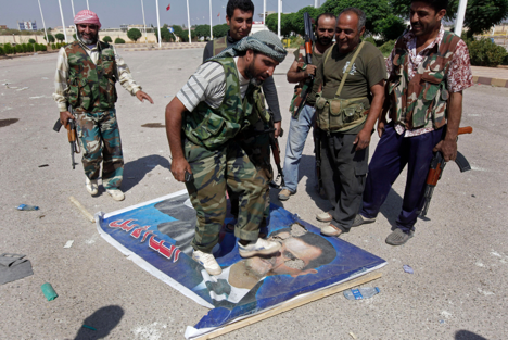 Seroang anggota Tentara Pembebasan Suriah menginjak foto Presiden Suriah Bashar al-Assad.