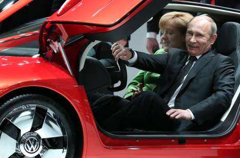 Il Presidente russo Vladimir Putin posa all'interno dell'auto ibrida Volkswagen XL 1,  alla fiera delle tecnologie industriali di Hannover (Germania), l'8 aprile 2013, con la cancelliera Angela Merkel (Foto: AFP / East News)