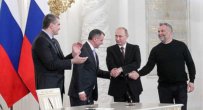 3月18日、プーチン大統領、セルゲイ·アクショーノフ・クリミア首相（左）、ウラジーミル・コンスタンティノフ・クリミア最高会議議長（左から二人目）、アレクセイ・チャルイ・セヴァストポリ特別市市長が、 クレムリンでのクリミア併合調印式の後、連邦議会議員の前に立つ＝コンスタンチン・ザウラジン / ロシースカヤ・ガゼタ（ロシア新聞）