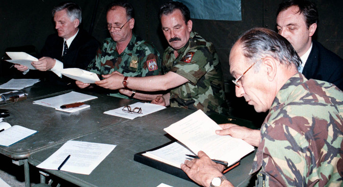 9. јун 1999. Британски генерал-поручник Мајк Џексон (десно) се спрема да потпише документ који југословенску војску и полицију обавезује да се повуче са Косова (касније назван „Кумановски споразум“). ВЈ је започела повлачење 10. јуна. Остали присутни, са десна на лево: портпарол Министарства спољних послова СРЈ Небојша Вујовић, генерал-мајор Благоје Ковачевић, генерал-пуковник Светозар Марјановић. Ваздушне операције НАТО-а заустављене су тек 19. јуна – 10 дана након потписивања Кумановског споразума, а одлуку о њиховом прекиду НАТО је донео још касније – 20. јуна. Извор: Reuters.